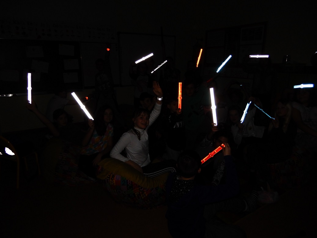 Świecące odblaski - pokazanie uczniom, jak odblaski świecą w ciemnym pomieszczeniu