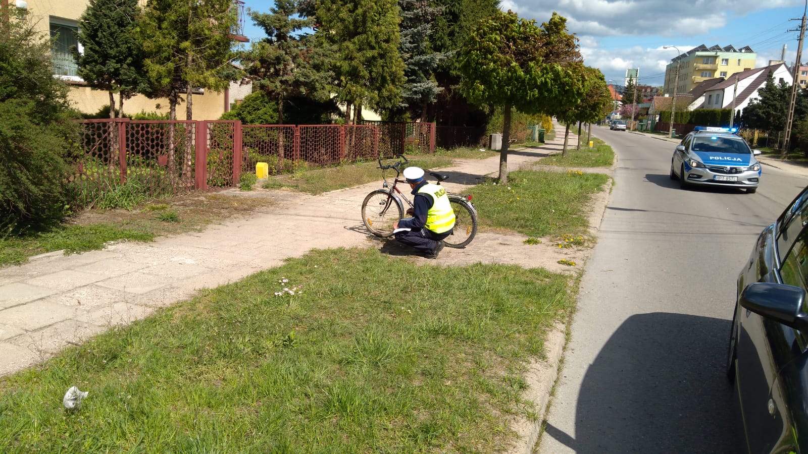 Miejsce zdarzenia drogowego w powiecie gołdapskim, policjant przy rowerze, samochód stojący na drodze