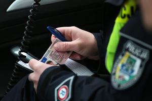 Policjant podczas kontroli trzymający w dłoniach blankiet prawa jazdy