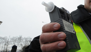 Policjant trzymający w ręku urządzenie do badania alkoholu w wydychanym powietrzu