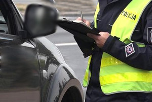 Policjant podczas kontroli drogowej przy samochodzie