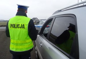 Umundurowany policjant stoi obok samochodu