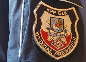 Rękaw kurtki z naszywką z logotypem oraz napisami KPP Ełk i Wydział Prewencji