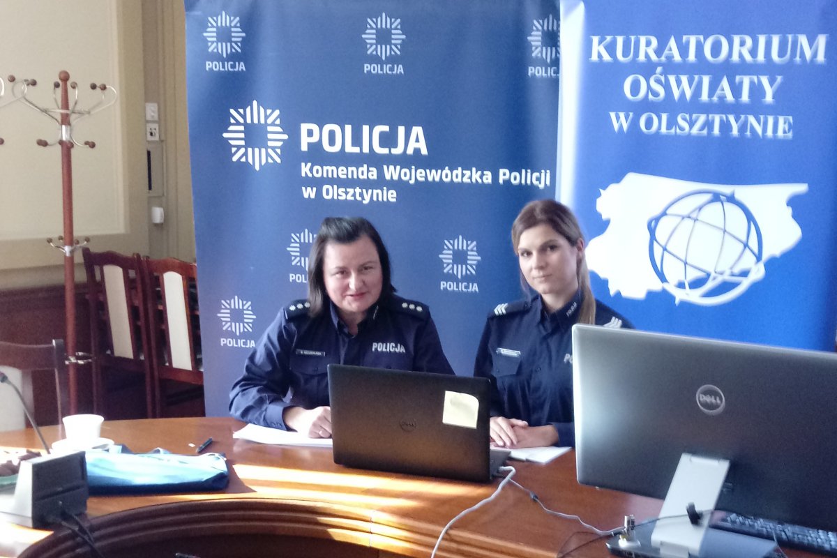 Policjantki siedzące za biurkiem i przed monitorem komputera podczas lekcji online
