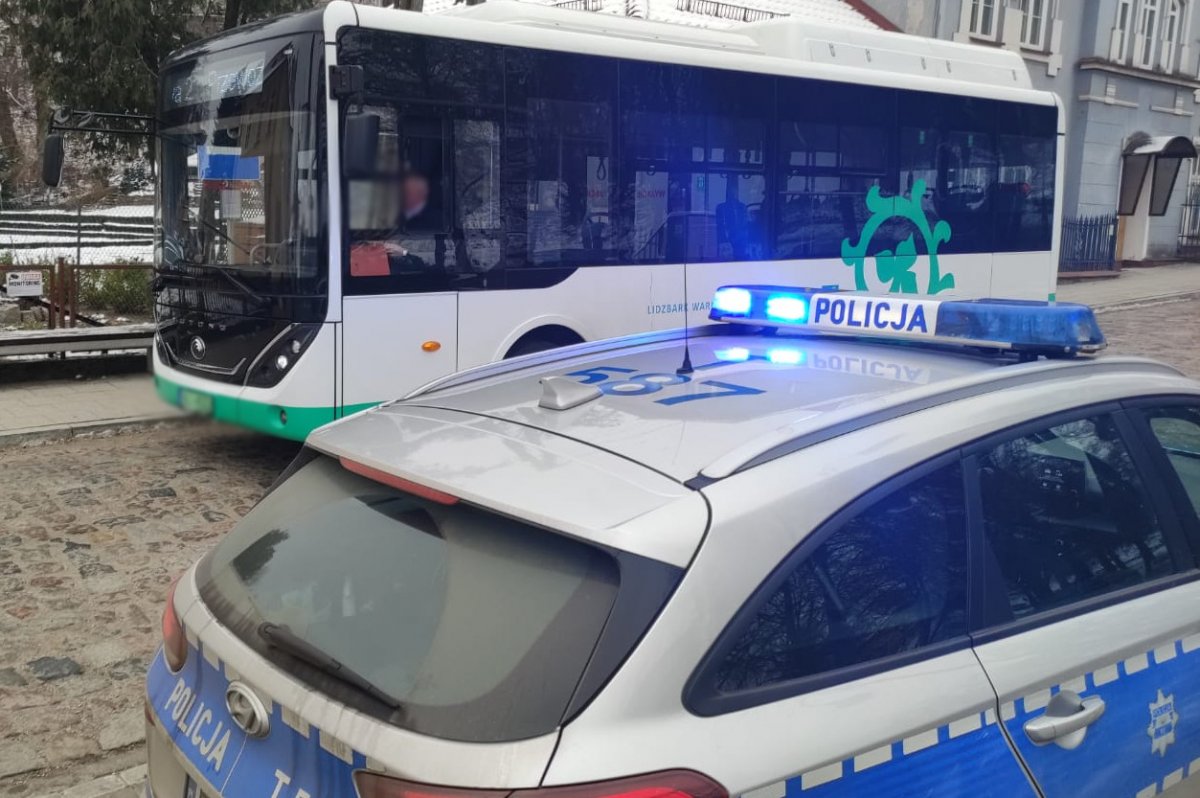 Lidzbarscy policjanci podczas kontroli autobusu komunikacji miejskiej. Autobus i radiowóz stojące na drodze
