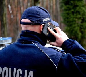 umundurowany policjant trzyma w przy uchu telefon komórkowy