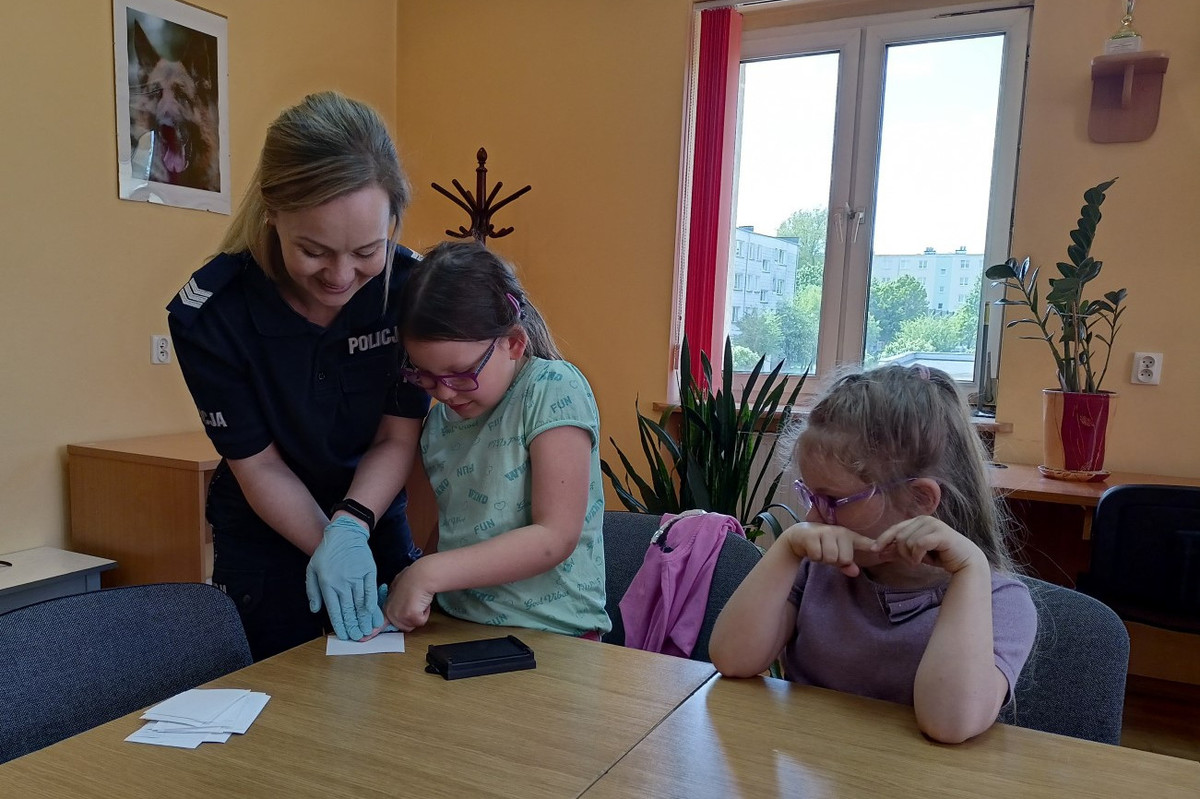 Policjantka podczas spotkania z dziećmi prezentuje w jaki sposób pobierane są odciski palców