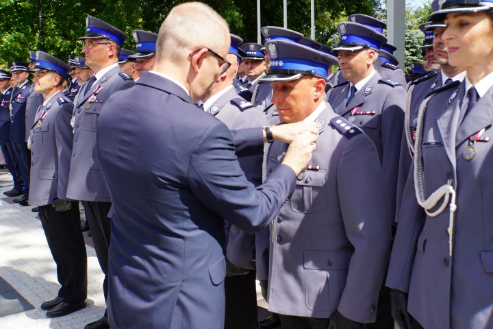 Minister Spraw Wewnętrznych i Administracji odznacza medalem policjanta stojącego w szeregu