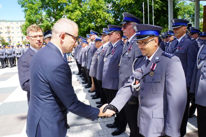 Minister Spraw Wewnętrznych i Administracji odznacza medalem policjanta stojącego w szeregu