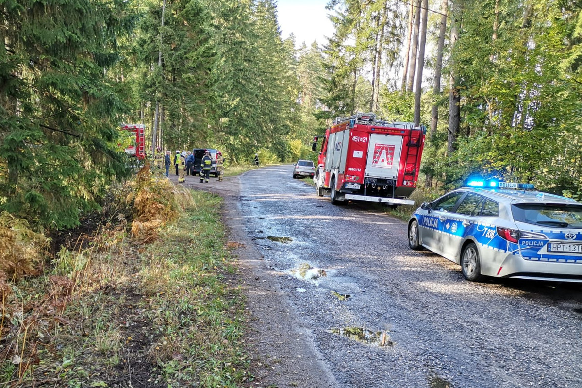 Miejsce zdarzenia drogowego w powiecie gołdapskim. Samochody służb ratunkowych stojące na drodze w lesie