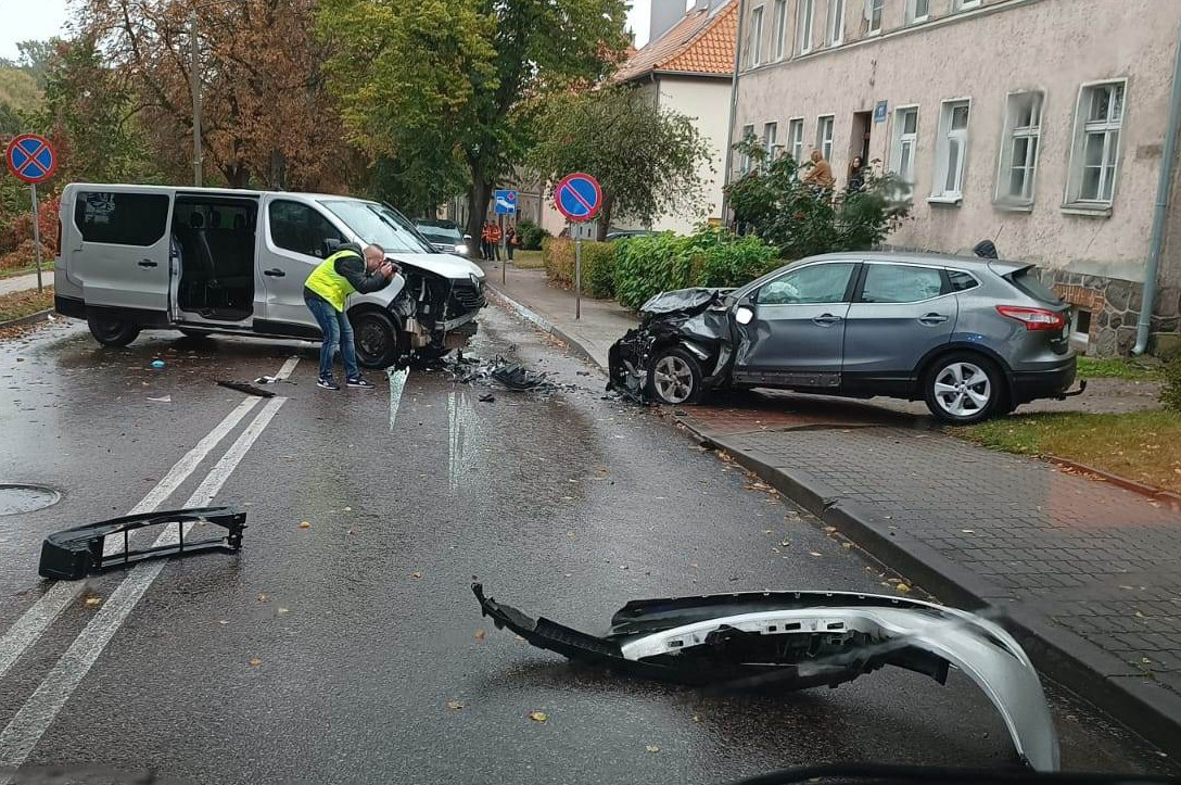 Miejsce zdarzenia drogowego w powiecie kętrzyńskim. Rozbity samochód na drodze i policjant fotografujący to miejsce