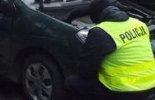 Policjant kucający przy samochodzie