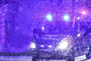 radiowóz z włączonymi światłami podczas śnieżycy