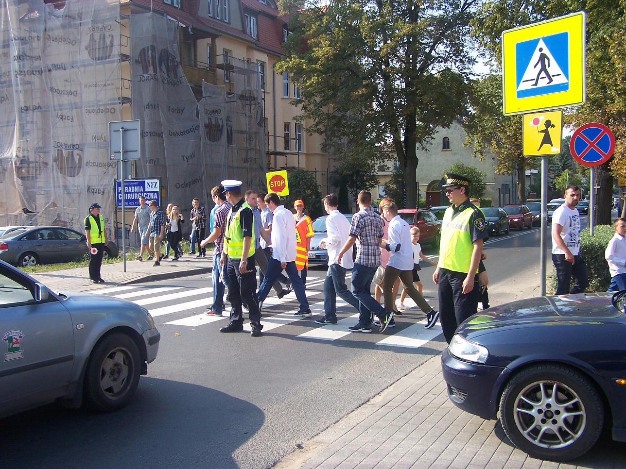 Policjanci pomagają uczniom przejść przez przejście dla pieszych